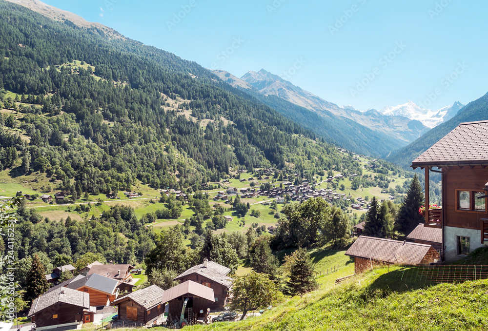 Wooden houses in the meadows of the Swiss Alps in the Saint Luc valley on a sunny day. Wooden houses in the meadows of the Swiss Alps in the Saint Luc valley on a sunny day.