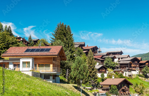 Wooden houses in the meadows of the Swiss Alps in the Saint Luc valley on a sunny day.