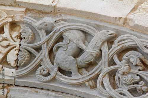 belva che cattura un pesce; rilievo sull'arco del portale maggiore della Cattedrale di Trani (Puglie) photo