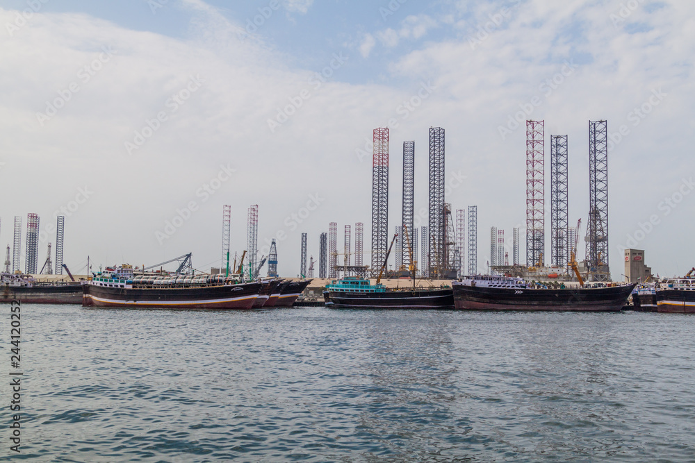 Boats, oil derricks and cranes in the Khalid port in Sharjah, United Arab Emirates.
