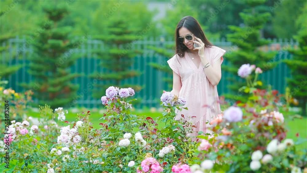 Young girl in a flower garden among beautiful roses. Smell of roses Young girl in a flower garden among beautiful roses. Smell of roses