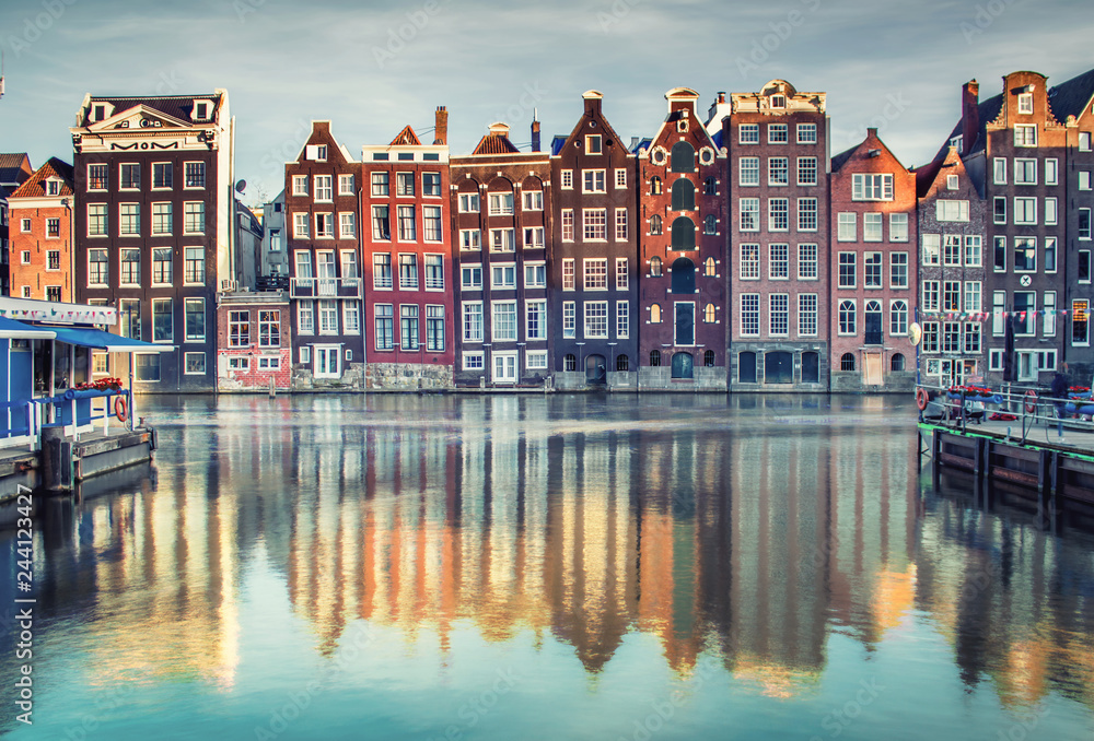 Colorful houses lining Damrak canal in Amsterdam, Netherlands at sunset