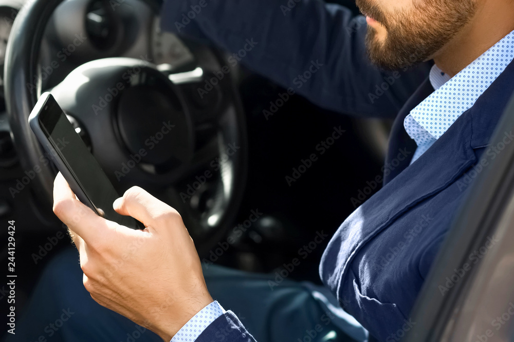 Handsome bearded man use smartphone in car