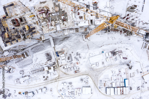construction area in winter, aerial top view. tower cranes and equipment building new apartments in snow