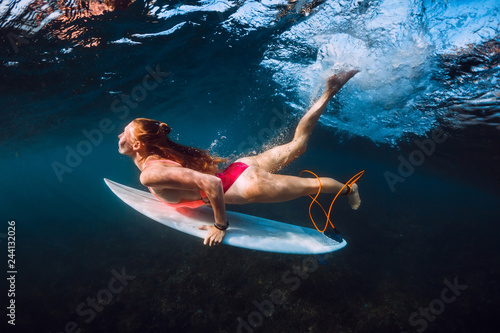 Attractive surfer woman dive underwater under wave.