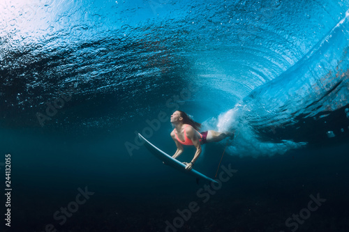 Fototapeta Surfer woman dive underwater with under barrel wave.