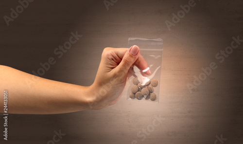 Naked, female hand giving drugs in plastic bag photo