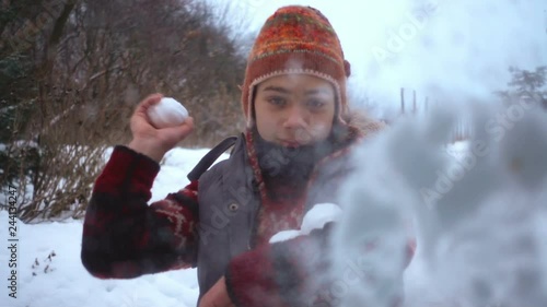 Teen boy throws a snowball into the glass of a camera. Slow motion. Portrait of a boy who plays snowballs slow motion.