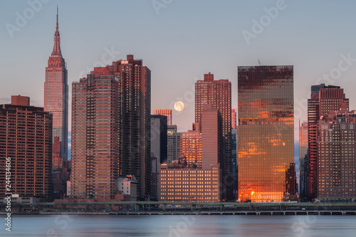 View on Manhattan with full moon from east river at sunrise