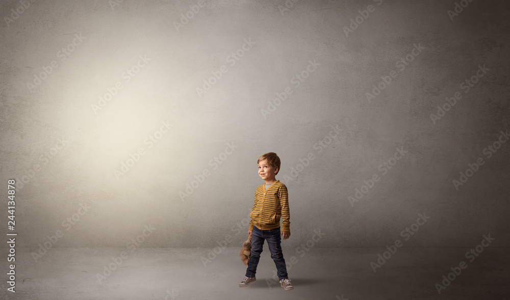 Obraz premium Little waggish kid staying alone in a big empty room with his plush 