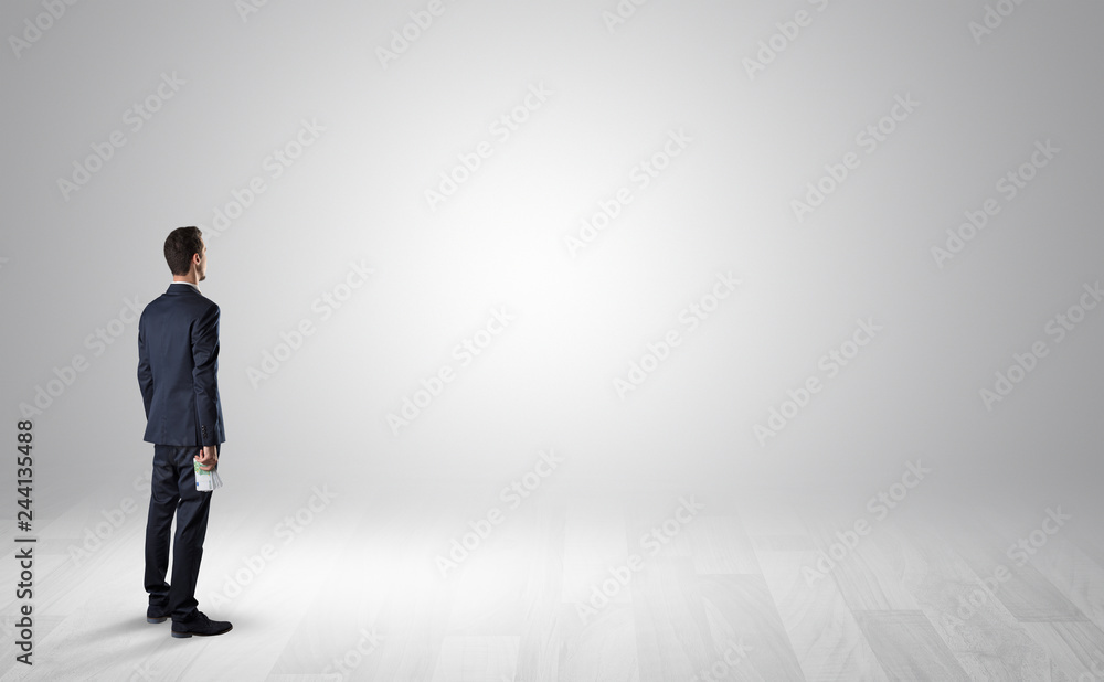 Man standing with his back in an empty room with object in his hand Man standing with his back in an empty room with object in his hand
