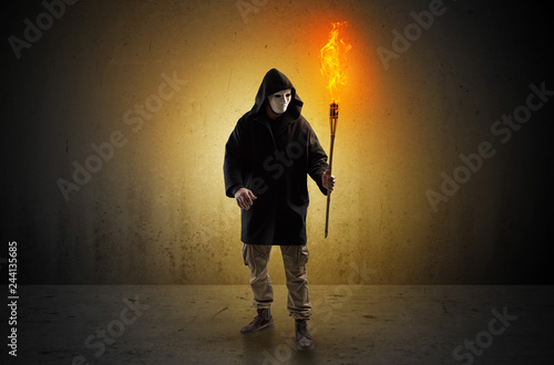 Ugly scary man with burning flambeau walking in an empty space