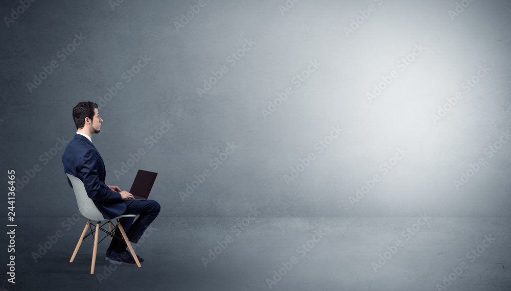 Businessman staying in an empty grey dark room with stuffs on his lap
Businessman staying in an empty grey dark room with stuffs on his lap