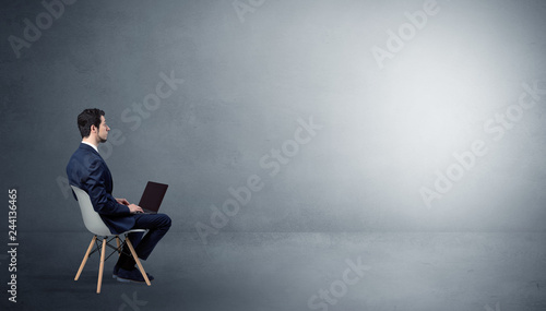 Photography Businessman staying in an empty grey dark room with stuffs on his lap