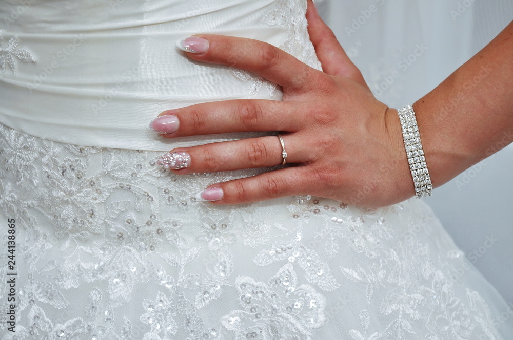 Bride standing with hand on hip in her wedding dress and engagement ring- flowers on wedding dress Bride standing with hand on hip in her wedding dress and engagement ring- flowers on wedding dress