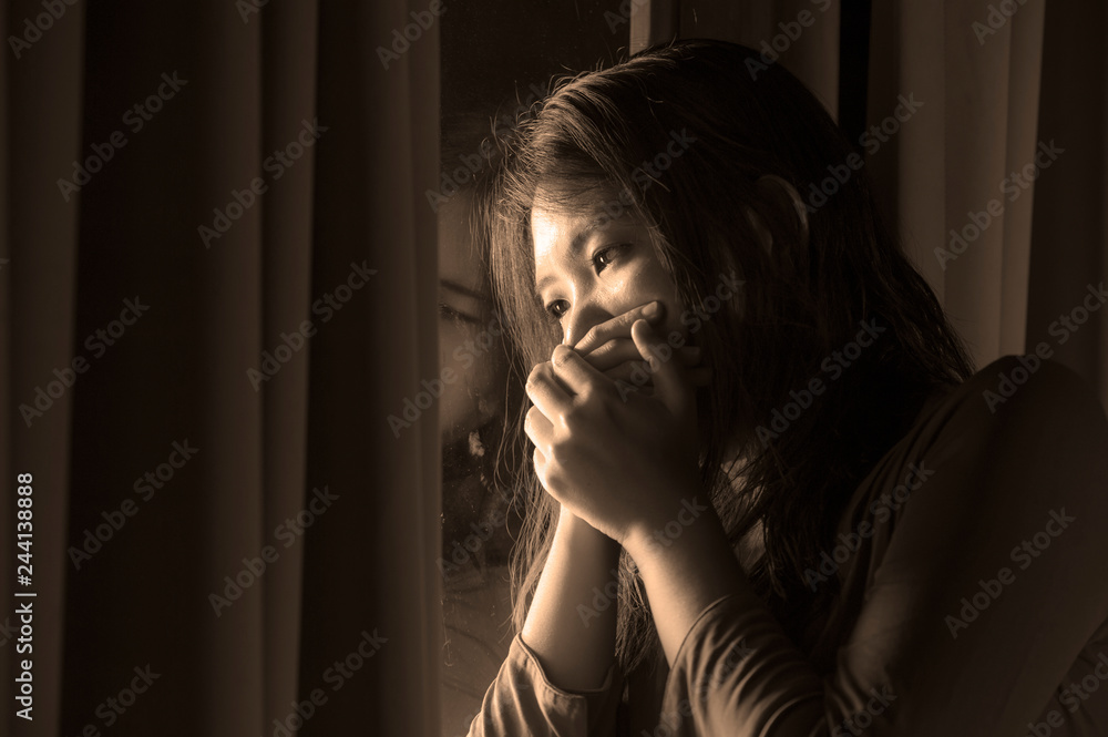 dramatic portrait of young sad and depressed Asian Korean woman crying desperate broken heart suffering depression and anxiety in dark light at home curtains window dramatic portrait of young sad and depressed Asian Korean woman crying desperate broken heart suffering depression and anxiety in dark light at home curtains window