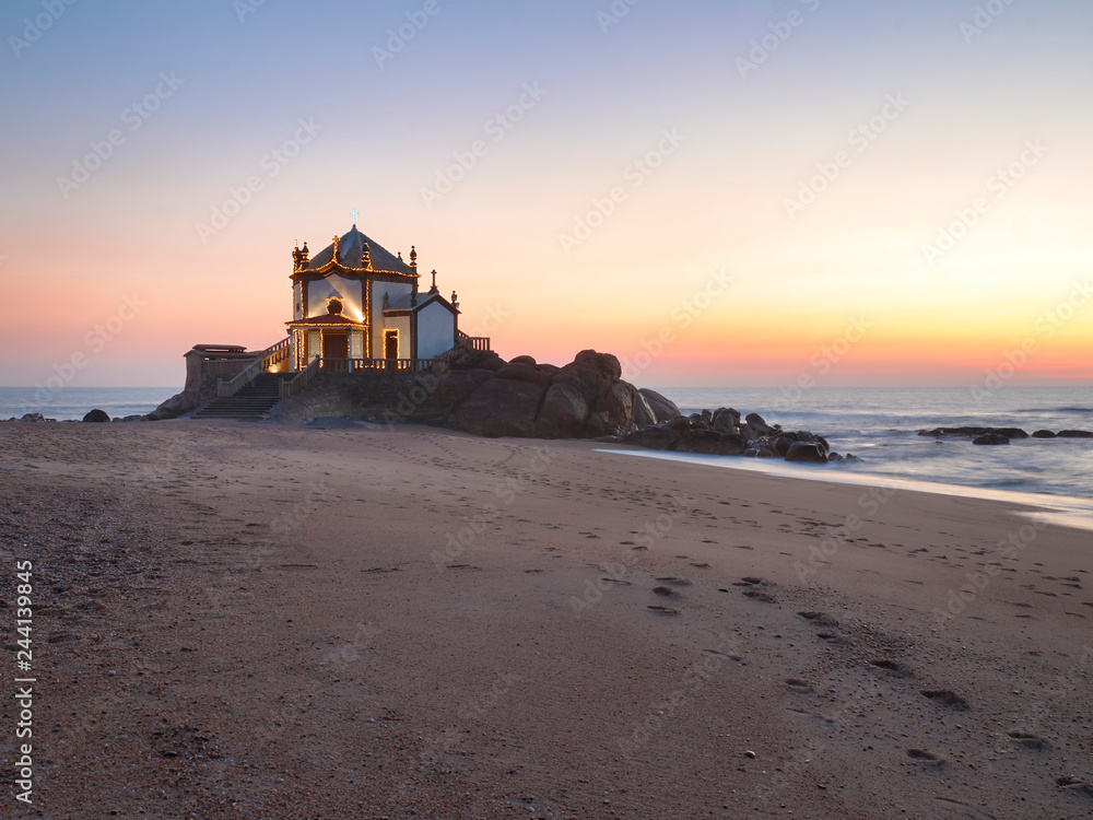 Landscape over the beach of miramar with view to chapel of senhor da Pedra at blue hour