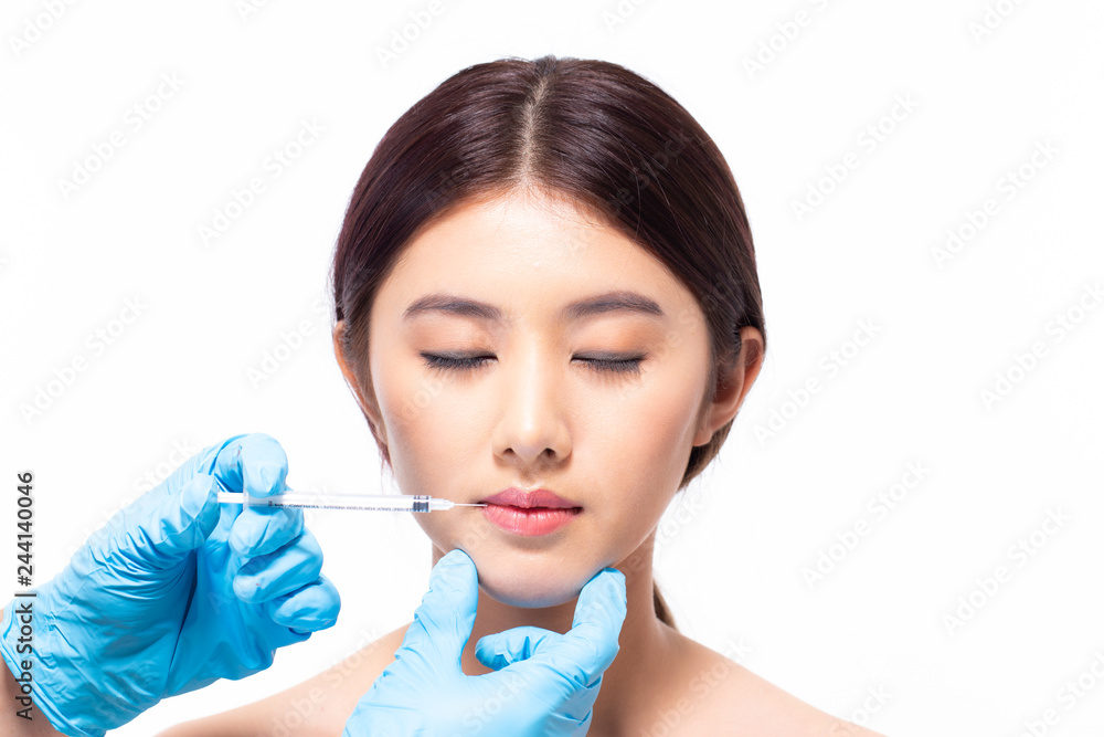 Young asian woman is getting collagen injection into her lips. Beauty female face surgery close up portrait. isolated on white background. Young asian woman is getting collagen injection into her lips. Beauty female face surgery close up portrait. isolated on white background.