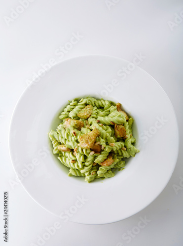 Delicious chicken with green sauce pasta over white background