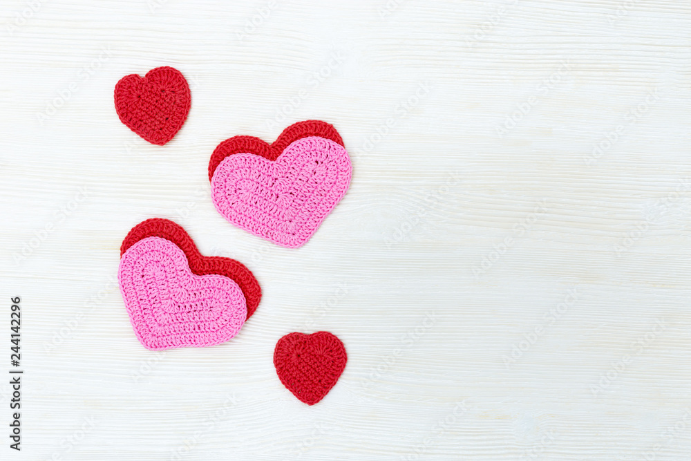 Fototapeta premium Knitted hearts on white wooden background with copy space. Flat lay. Top View.