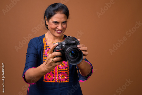 Mature beautiful Indian woman photographer using DSLR camera