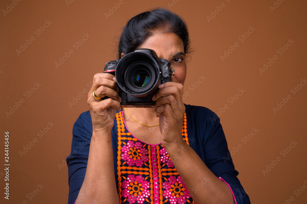 Mature beautiful Indian woman photographer using DSLR camera Mature beautiful Indian woman photographer using DSLR camera