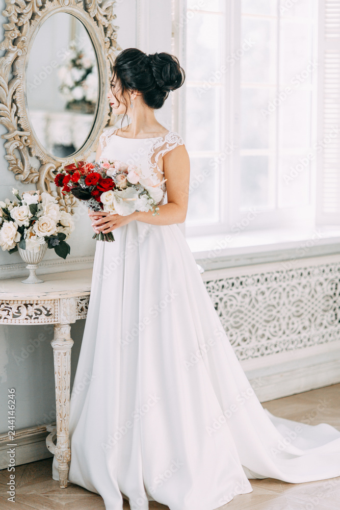 Bride in a bright Studio with a bouquet. Wedding dress and mirror. Bride in a bright Studio with a bouquet. Wedding dress and mirror.
