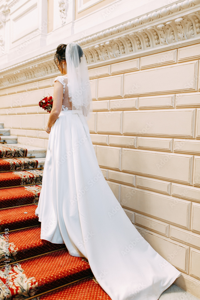 Beautiful girl in a wedding dress with a bouquet. Bride in a bright Sunny Studio. Beautiful girl in a wedding dress with a bouquet. Bride in a bright Sunny Studio.