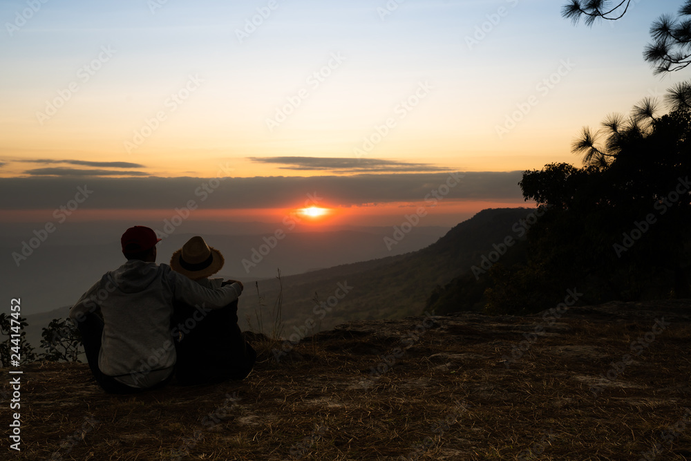 Image of sunset or sunrise on orange and yellow horizon with a silhouette of a couple in natural surrounding Image of sunset or sunrise on orange and yellow horizon with a silhouette of a couple in natural surrounding