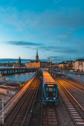 Evening cityscape with subway train crossing the bridge of Gamla Stan, Stockholm, Sweden. City hall and cathedral in background