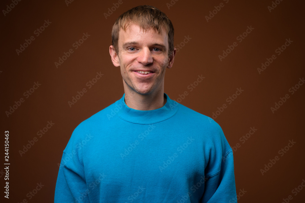 Man wearing blue sweater against brown background Man wearing blue sweater against brown background