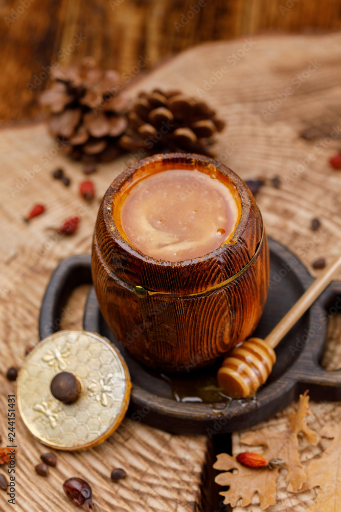 Barrel with fresh delicious honey on a wooden saw. Barrel with fresh delicious honey on a wooden saw.