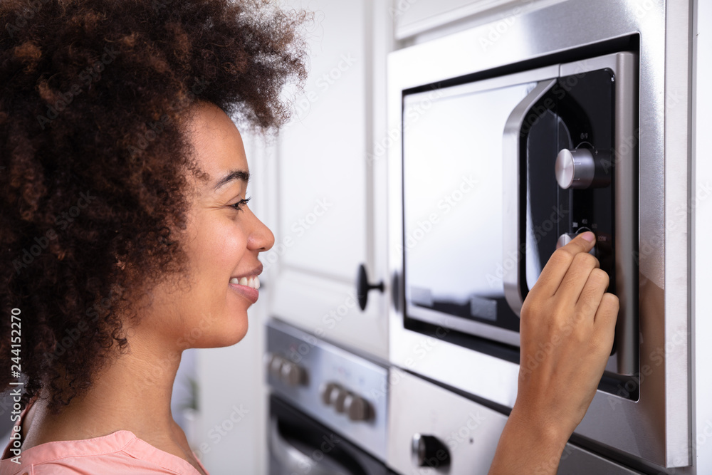 Woman Adjusting Temperature Of Microwave Oven Woman Adjusting Temperature Of Microwave Oven