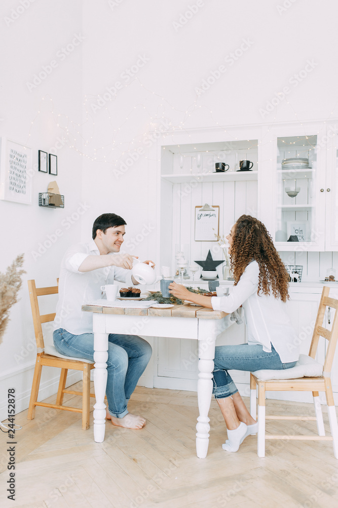Young couple eating sweets at the table. Photo shoot in a bright interior Studio for the New year. Young couple eating sweets at the table. Photo shoot in a bright interior Studio for the New year.