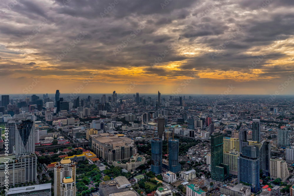 Aerial view of Bangkok skyline and skyscraper with light trails at sunset.