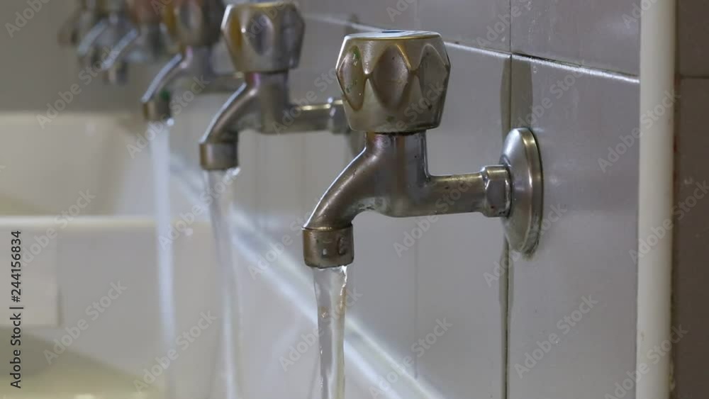 Hand of man closes many steel taps in the bathroom Hand of man closes many steel taps in the bathroom