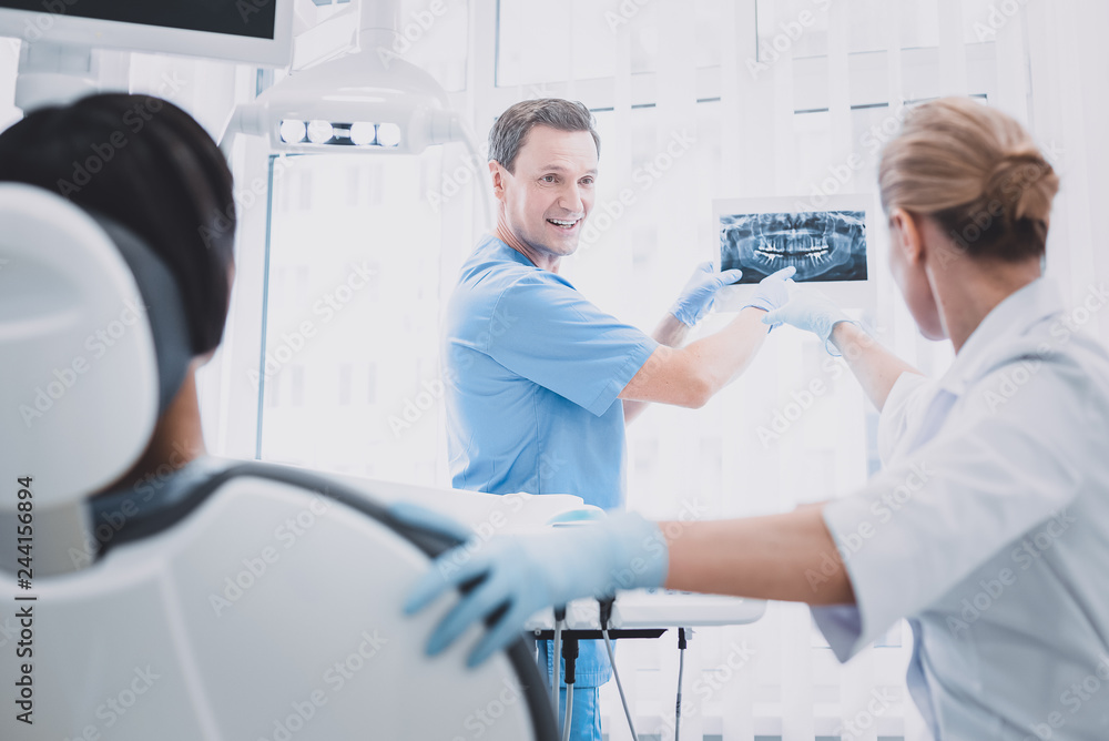 Cheerful male person demonstrating x-ray picture to colleague Cheerful male person demonstrating x-ray picture to colleague
