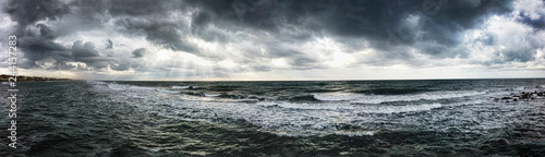 Dramatic weather panoramic view over the sea threatening waves crashing at the shore with overcast sky and sunbeams on the water - find more in my profile © Equatore