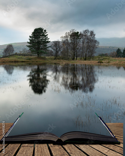 Stunning landscape image of dramatic storm clouds over Kelly Hall Tarn in Lake District during late Autumn Fall afternoon coming out of pages of open story book photo