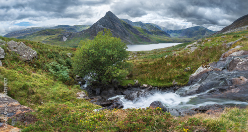 Stunning panorama landscape image of stream flowing over rocks near Llyn Ogwen in Snowdonia during eary Autumn with Tryfan in background photo