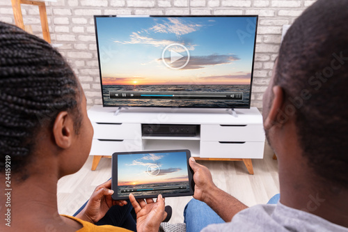 Fototapeta Naklejka Na Ścianę i Meble -  Couple Connecting Television Through Wireless On Tablet