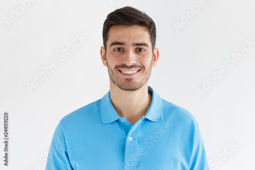 Close up portrait of young smiling handsome man in blue polo shirt isolated on gray background © Damir Khabirov