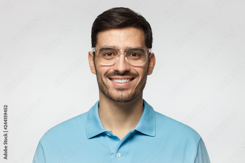 Smiling modern nice guy in blue polo shirt and trendy trasparent eyeglasses, isolated on gray background Smiling modern nice guy in blue polo shirt and trendy trasparent eyeglasses, isolated on gray background