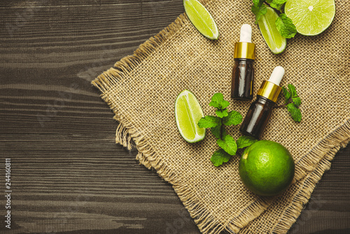 Aromatherapy essential oil bottle with lime fruit and leaf mint.