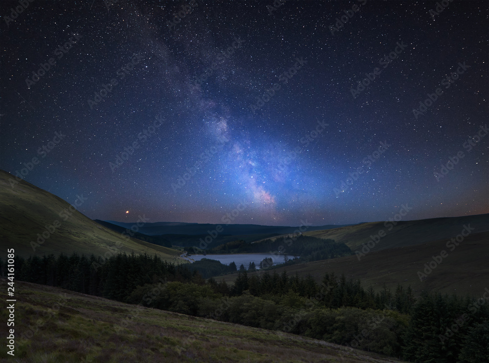 Vibrant Milky Way composite image over landscape of mountains in distance