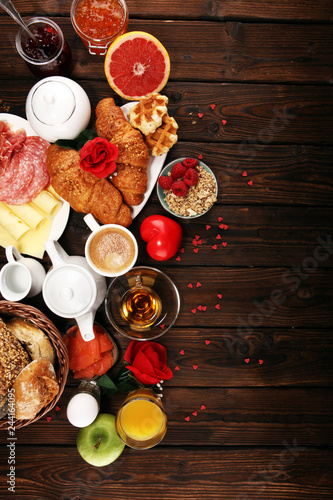 breakfast on table with bread buns, croissants, coffe and juice on valentines day.