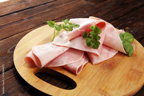 Sliced ham with parsley on table. Fresh prosciutto. Pork ham sliced.
