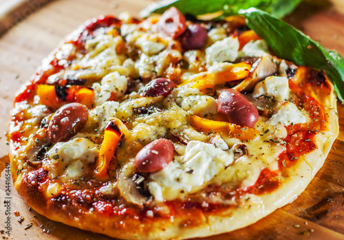 vegetarian pizza with Mozzarella cheese, olives, mushrooms, pepper and fresh basil. Italian pizza on wooden table background
