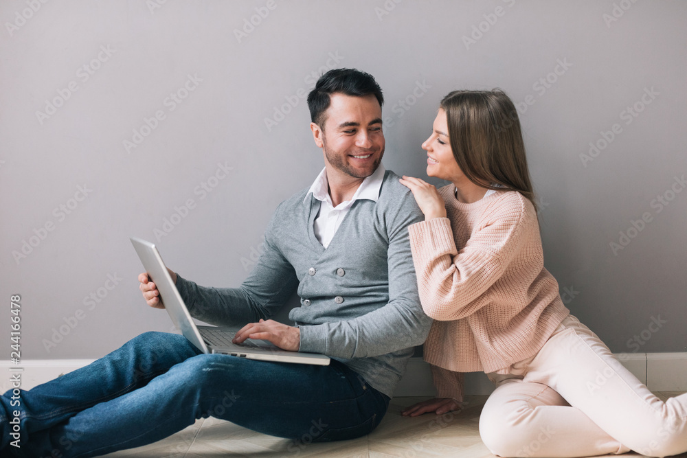 Young happy couple using laptop sitting on floor. Young happy couple using laptop sitting on floor.