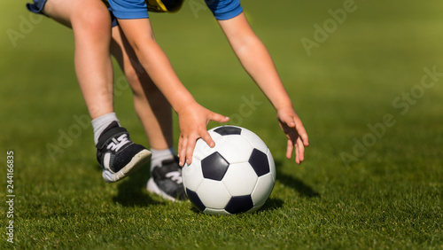 Child playing soccer. Preschool soccer leagues. Kid catching soccer ball on the field. Closeup soccer picture